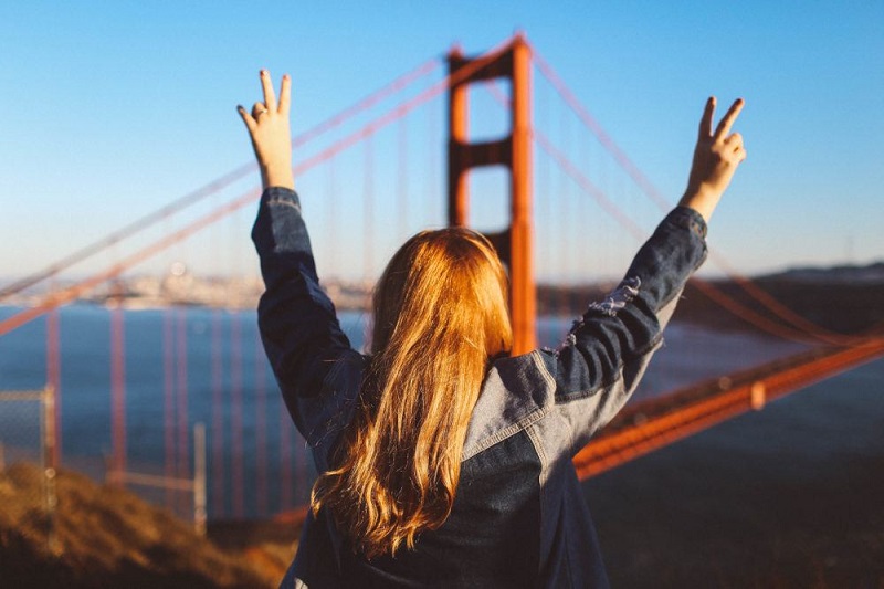 Menina tirando foto com a ponte Golden Gate de fundo